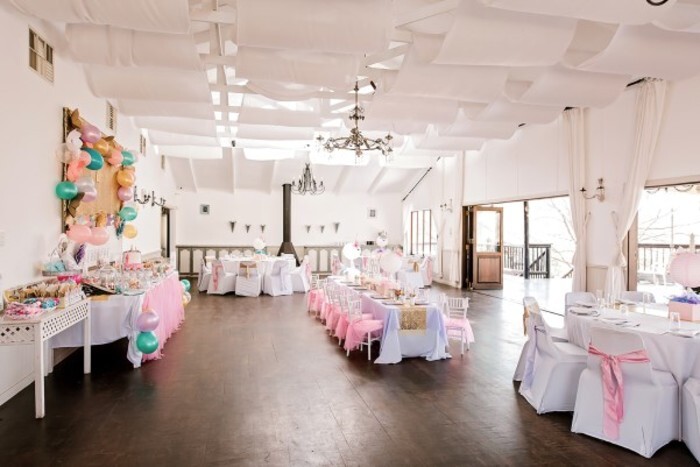 Large round wooden tables and catering chairs with white covers and theme matching tiebacks.