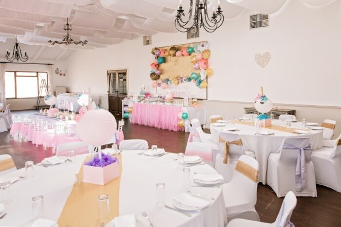 Catering chairs with white covers and theme matching tiebacks as well as large round wooden tables.